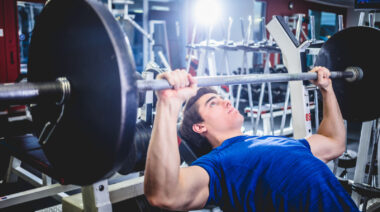 Person in gym performing barbell incline bench press