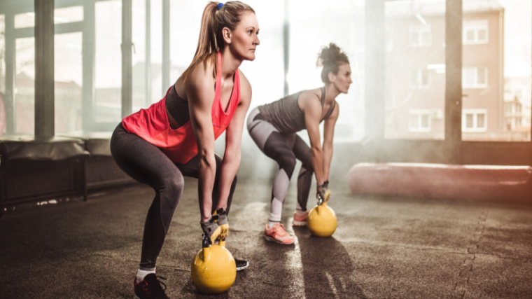 two people in gym performing kettlebell exercise