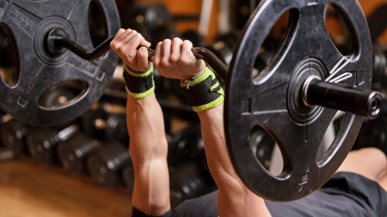 muscular person in gym holding barbell overhead