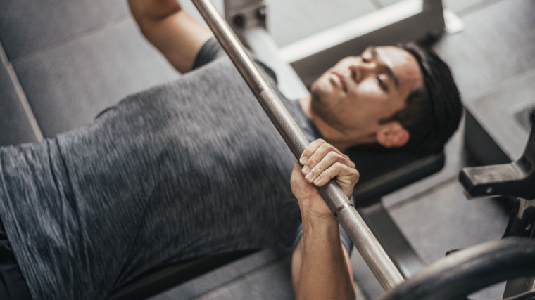 person in gym performing bench press