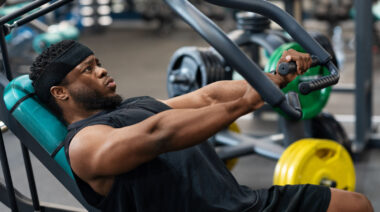 Muscular person in gym using chest press machine