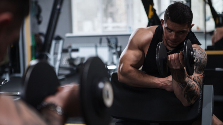 muscular person in gym doing biceps curl