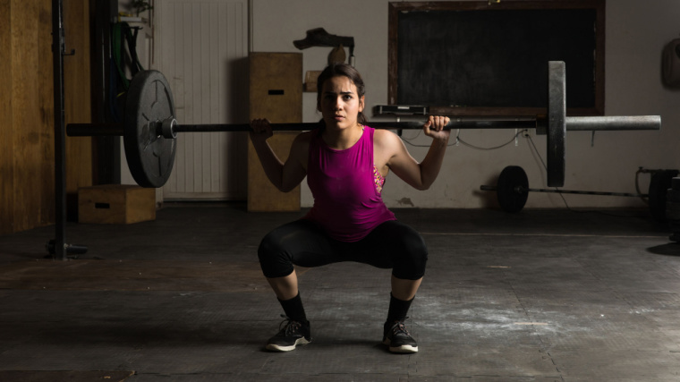 person in gym doing barbell squat