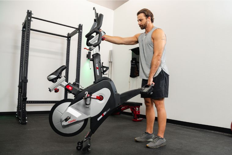 A young man tilting the Diamondback 1260Sc bike to wheel it around his garage