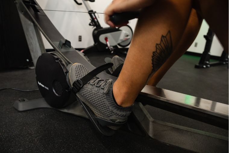 A close-up of an athlete's foot strapped into the Hydrow Wave rower