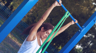 Woman outdoors using resistance band for pull-ups