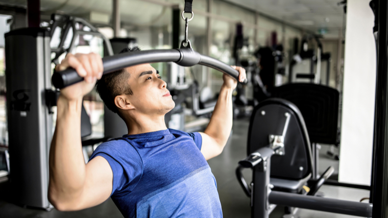 person in blue shirt performing pulldown back exercise