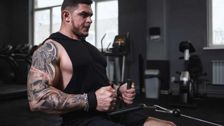 Large bodybuilder in gym performing back exercise