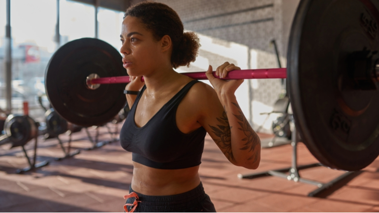 person in gym holding barbell on back