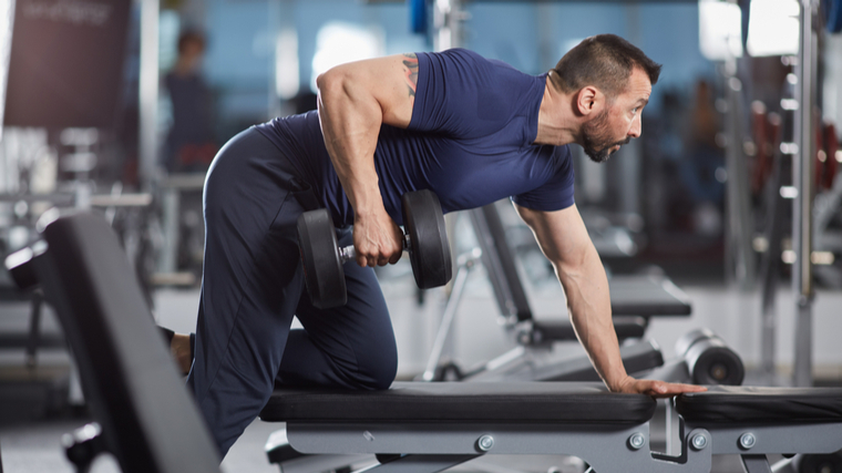 Muscular man performing dumbbell row