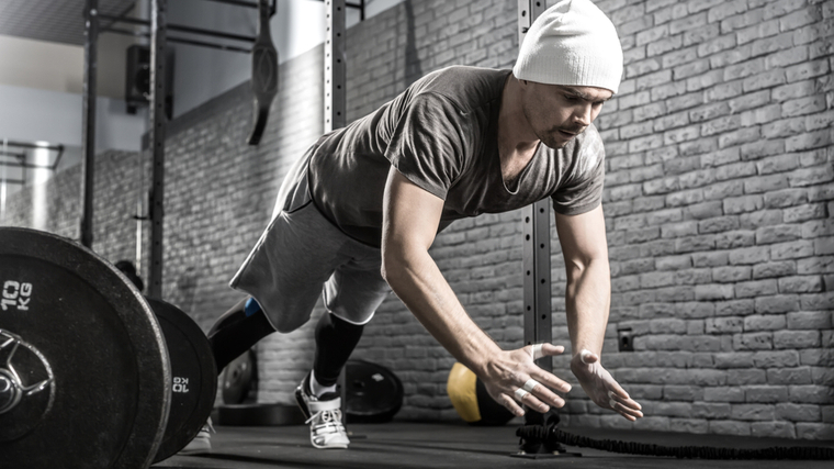 Man in gym performing explosive push-up.