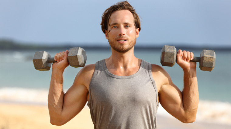 Man outdoors performing dumbbell shoulder press