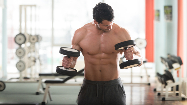 Muscular shirtless man performing dumbbell curl