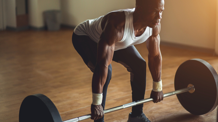 person in tank top deadlifting barbell