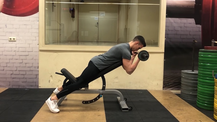 person in gym curling barbell